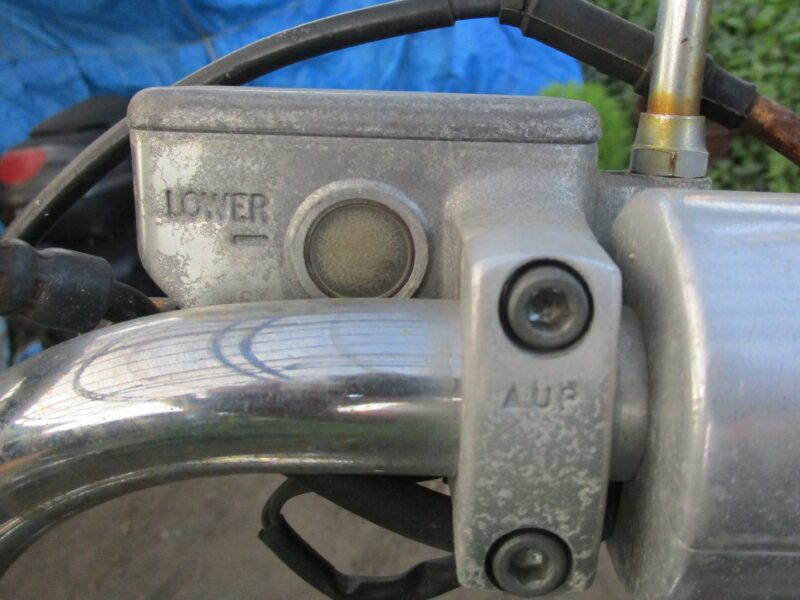 ホンダ・ジョーカー90に半年以上乗らずに放置しておいた結果、マスターシリンダーのオイル確認窓は曇って(細かくひび割れて)しまっています。