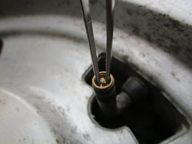 タイヤのエアバルブ部のコアバルブを、ピンセットを付けって取り外している画像