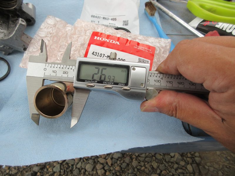 ホンダ・ジョーカー90のキャリパーピストン外径をデジタルノギスで測定する様子
