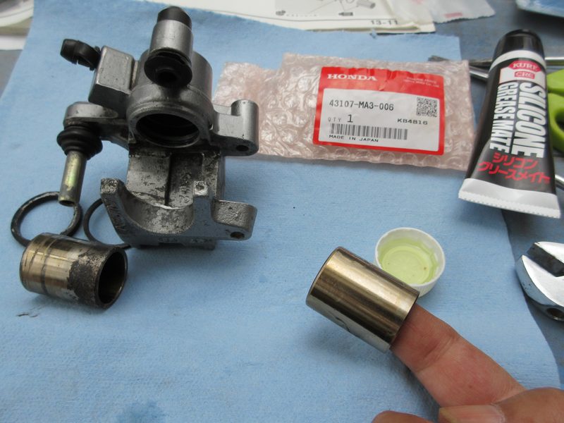 新しいピストンシール類を組んだキャリパーシリンダーへ新品ピストンを指で手で押し込む作業