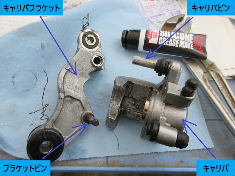 キャリパーブラケットとキャリパー本体、およびグリスを塗布したキャリパピンの位置を示す写真